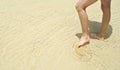 Persons legs standing in shallow water on white coral sand Royalty Free Stock Photo