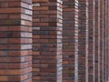 Perspective diagonal view on abstract brown red brick wall with columns with blured background. Architecture element brown brick w