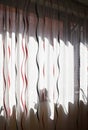 Perspective of long white curtain with black and red wavy strips and shadows