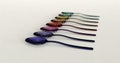 Perspective of rainbow color metal spoons arranged in line.