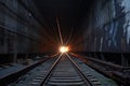 perspective shot of long, dark subway tunnel with light at the end