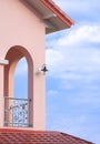 Perspective side view of arches wall on balcony of modern Tuscan pink house style against white clouds and blue sky