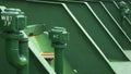 Side view of metal pipes on green oil tanks in crude oil tanker ship