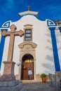 Ericeira, Mafra PORTUGAL - September 23, 2022 - Perspective of a stone cross and facade of the Church of SÃÂ£o Pedro with a person