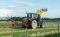 Perspective of tractor with raised rake as it turns in a plot of dry grass swaths
