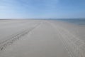 Perspective of tyre tracks on sandy beach with dark blue cloudy sky