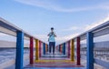 Asian young man in protective mask using mini digital camera to taking video on colorful wooden bridge at sea viewpoint Royalty Free Stock Photo