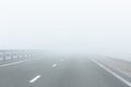 Perspective view of asphalt  empty road with guardrail and marking lines in a white fog Royalty Free Stock Photo