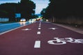 Perspective view of bike lane near street with blurred cars and lights Royalty Free Stock Photo