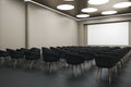 Perspective view on blank white screen with space for advertising text illuminated from top in empty auditorium with black chairs Royalty Free Stock Photo