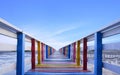 Perspective view of colorful rainbow wooden bridge extends into the sea against blue sky background Royalty Free Stock Photo