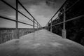 Perspective view of concrete bridge with metal fence on mangrove forest against dramatic grey sky and clouds. Grief, hopeless