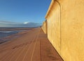 View of the concrete seawall in blackpool with steps leading down to the beach in warm afternoon sunlight with blue