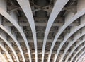 Perspective view of curved arch shaped steel girders under an old road bridge with rivets and struts painted grey Royalty Free Stock Photo