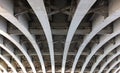 Perspective view of curved arch shaped steel girders under an old road bridge with rivets and struts painted grey Royalty Free Stock Photo