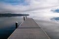 Perspective view of dock over calm lake with blue sky, clouds, and fog Royalty Free Stock Photo