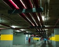Perspective view of empty indoor car parking lot at the mall. Underground concrete parking garage with open lamp at night. Wiring