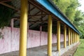 Perspective view of an empty small building with a wall and some yellow pillars