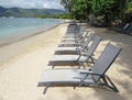 Perspective view of empty sun loungers on tropical beach with turquoise Caribbean sea. Row of empty deckchairs on the shore in the Royalty Free Stock Photo