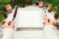 Perspective view girl holds fork and knife in hand and is ready to eat. Empty white square plate on wooden christmas background. Royalty Free Stock Photo
