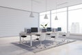 Perspective view on light wooden work table with modern computers surrounded by white chairs in sunlit open space office with Royalty Free Stock Photo