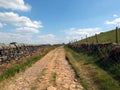 Perspective view of a long narrow country lane running uphill surrounded by stone walls west yorkshire countryside surrounded