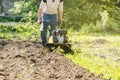 Perspective view of man plowing raw in soil by motor cultivator Royalty Free Stock Photo