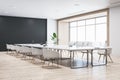 Perspective view of empty conference room with white office desk and chairs, black wall, wooden floor, and window with city Royalty Free Stock Photo