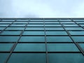 Perspective view of a modern glass office building against a cloudy blue sky reflected in the windows Royalty Free Stock Photo