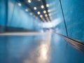 Perspective view of a modern hallway with a smooth reflective floor and blue walls illuminated by warm ceiling lights creating a Royalty Free Stock Photo