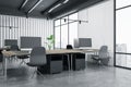 Perspective view on modern interior design coworking office with dark grey chairs, concrete floor, wooden tables and city view Royalty Free Stock Photo