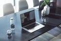 Perspective view on modern laptop on concrete effect table with glass of water and light vases in sunlit office. 3D rendering