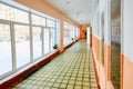 Perspective view of an old school or office building corridor , empty narrow, high and long , with many room doors and Windows.