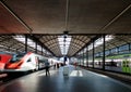 Perspective view of a platform in Lucerne Central Railway Station with sunlight cast on trains parking by the platform