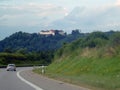 A perspective view of the road along which the car is traveling. An old house is built on the hill in the background Royalty Free Stock Photo