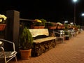 A perspective view of the sidewalk with a metal railing bench and chairs and flower pots along them Royalty Free Stock Photo