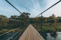 Vintage rustic suspension bridge over river in autumn. River crossing concept. Royalty Free Stock Photo