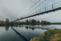 Vintage rustic suspension bridge over river in autumn. River crossing concept. Royalty Free Stock Photo