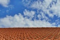 Perspective view of a tiled roof under a blue cloudy sky Royalty Free Stock Photo