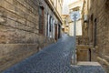 Perspective view to empty ascending narrow small street with traditional old black cobblestones pavement