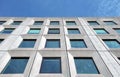 Perspective view of a white concrete office building against a bright blue sky reflected in the windows, with geometric brutalist Royalty Free Stock Photo
