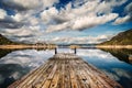 Perspective view of a wooden pier in a completely calm lake with reflections of the sky Royalty Free Stock Photo