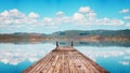 Perspective view of a wooden pier in a completely calm lake with reflections of the sky Royalty Free Stock Photo