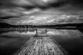 Perspective view of a wooden pier in a completely calm lake with reflections of the sky - long exposure Royalty Free Stock Photo