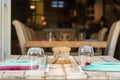 Perspective view of a wooden table with chairs, glasses and plates outdoors in a Greek taverna in Hydra, Greece