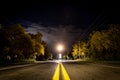 Perspective view of yellow lane lines of an old asphalt road in a lonely quiet night, with storm coming from the clouds