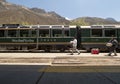 Workers carrying trays in front of Machupicchu train, mountains on the background