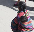 Peru - october Native woman dressed in traditional colourful clothing walks at the local market with her baby on her back