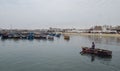 Man paddles his canoe in front of a line of boats at Paracas port Peru