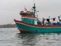 Orange and teal fisherman boat anchored at sea, clothes drying hanging from wire